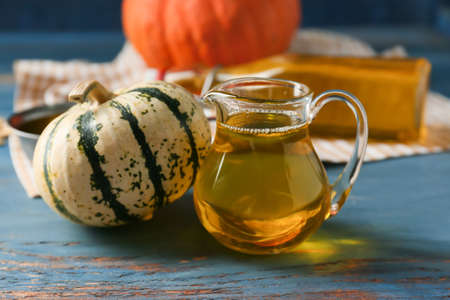 Jug of pumpkin seed oil on color wooden background, closeupの写真素材