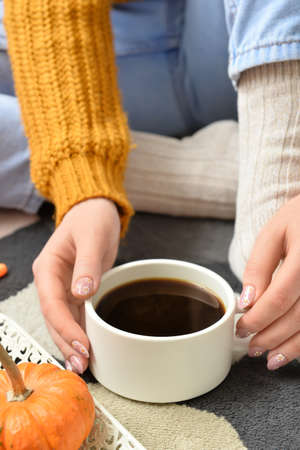 Woman drinking tasty pumpkin coffee on floor in roomの写真素材