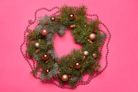 Beautiful Christmas wreath made of fir branches and balls on pink backgroundの写真素材