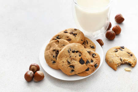 Plate with tasty homemade cookies, glass of milk and chestnuts on light background