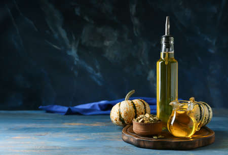 Bottle and jug of pumpkin seed oil on wooden tableの写真素材