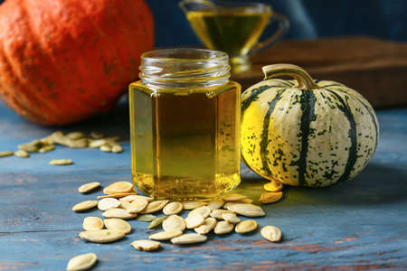 Jar of pumpkin seed oil on color wooden background, closeupの写真素材