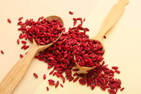 Spoons with dried barberries on yellow background