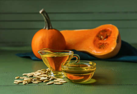 Bowl and jug of pumpkin seed oil on tableの写真素材
