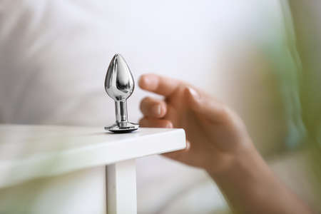 Young woman taking anal plug sex toy from bedside table, closeupの写真素材