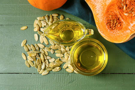 Bowl and jug of pumpkin seed oil on color wooden backgroundの写真素材