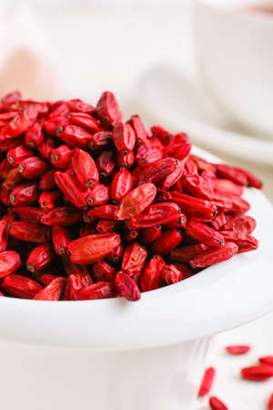 Bowl with dried barberries on light background, closeup