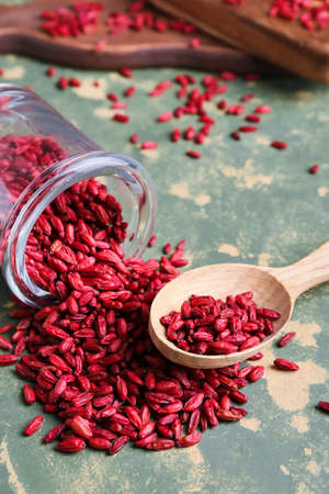 Jar and spoon with dried barberries on green grunge background