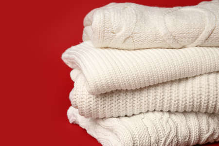 Stack of knitted sweaters on red background, closeupの写真素材