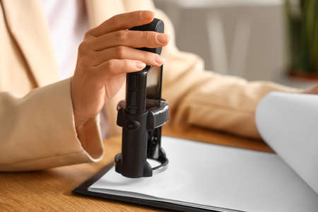 Female notary public attaching seal to document in office, closeupの写真素材