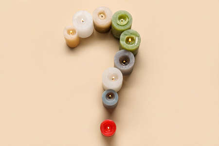 Question mark made of different burning candles on color background