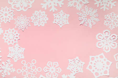 Frame made of beautiful paper snowflakes on pink background