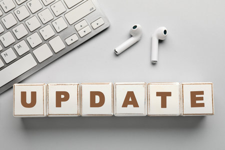 Word UPDATE made of cubes, PC keyboard and earphones on light backgroundの写真素材