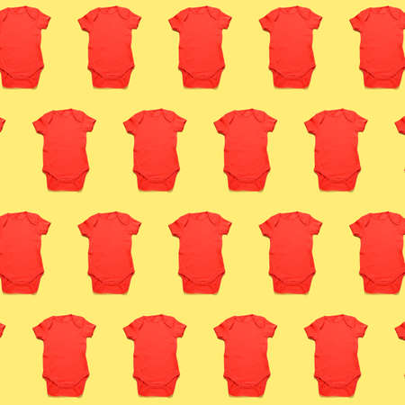 Many baby bodysuits on yellow background. pattern for designの写真素材