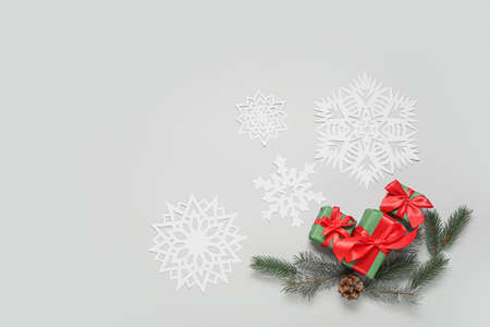Fir branches, gift boxes and beautiful paper snowflakes on light backgroundの写真素材
