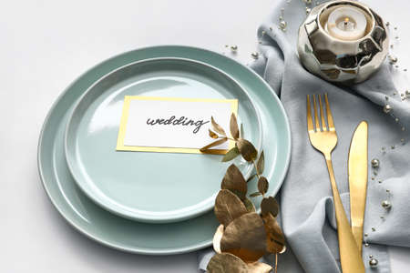 Beautiful table setting and wedding invitation on light background