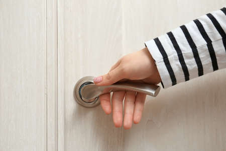 Woman holding silver handle of light wooden door, closeupの写真素材