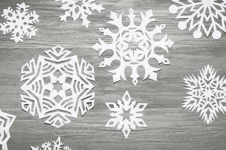 Beautiful paper snowflakes on gray wooden background