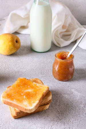 Bread with tasty pear jam and bottle of milk on tableの写真素材