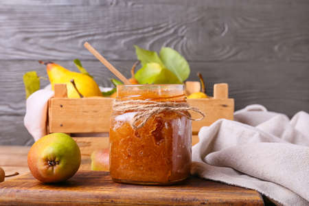 Glass jar of tasty pear jam on tableの写真素材