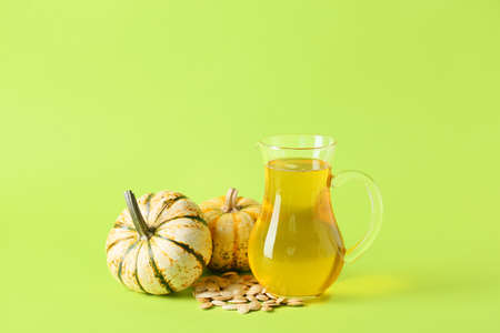 Jug of tasty pumpkin seed oil on color backgroundの写真素材