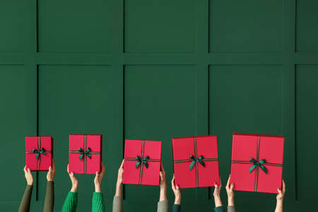 Many hands with Christmas gifts on color background