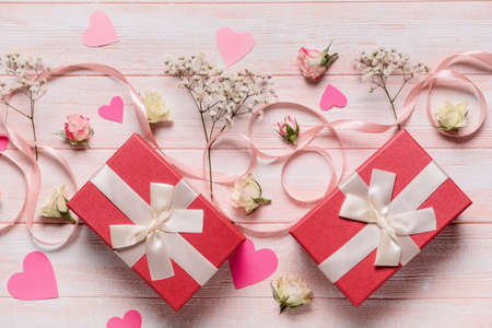 Gifts for Valentine's Day, flowers and ribbon on light wooden background