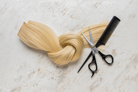 Blonde hair strand for donation with scissors and comb on grunge backgroundの写真素材
