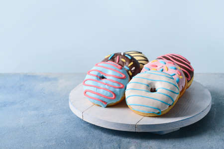 Board with different delicious donuts on tableの写真素材