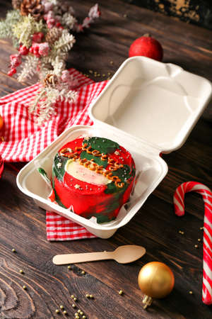 Plastic lunch box with tasty bento cake and Christmas decor on wooden backgroundの写真素材