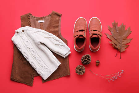 Baby clothes, shoes and natural forest decor on red backgroundの写真素材