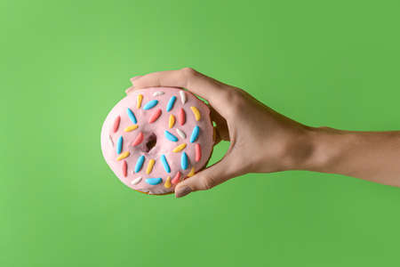 Woman holding delicious donut on green backgroundの写真素材
