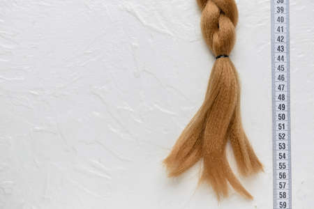 Braided red hair for donation with measuring tape on white backgroundの写真素材