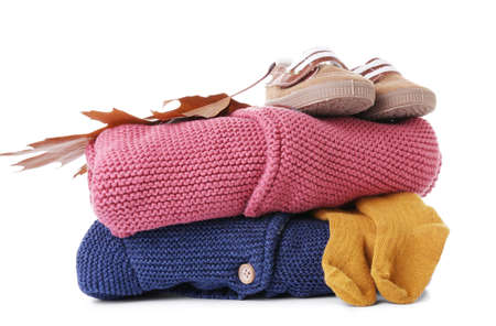 Stack of baby clothes, shoes and autumn leaf on white backgroundの写真素材