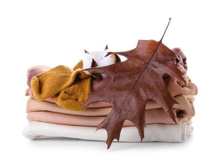 Stack of baby clothes, cotton flower and autumn leaf on white backgroundの写真素材