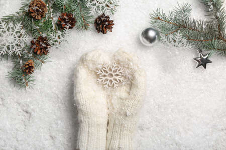 Woman in warm mittens holding snowflake, fir branches and pine cones on white background