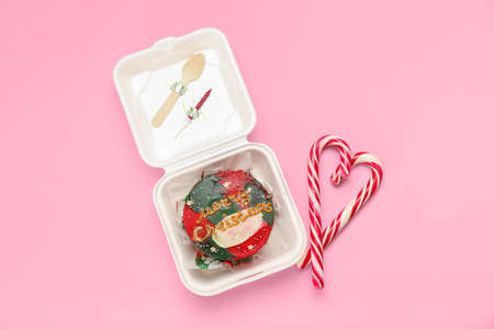 Plastic lunch box with Christmas bento cake and candies on pink background