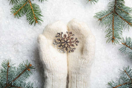 Woman in warm mittens with snowflake and fir branches on white backgroundの写真素材