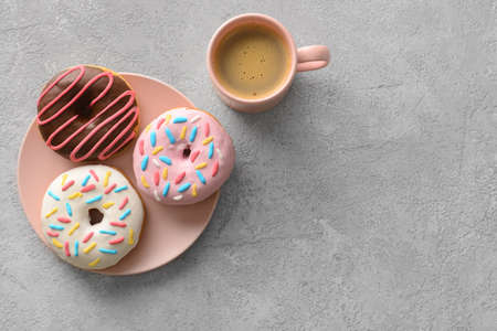 Plate with delicious donuts and cup of coffee on gray backgroundの写真素材