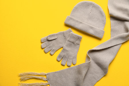 Warm gloves, hat and scarf on yellow backgroundの写真素材
