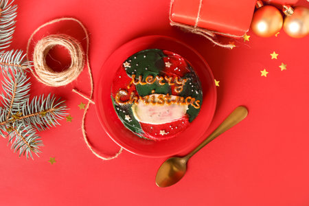 Plate with tasty bento cake and Christmas decor on red backgroundの写真素材