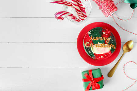 Plate with tasty bento cake and Christmas decor on light wooden backgroundの写真素材