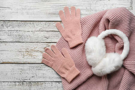 Warm gloves, scarf and earmuffs on light wooden backgroundの写真素材