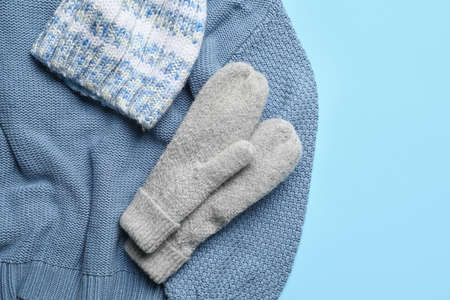 Warm mittens, sweater and hat on color background, closeupの写真素材