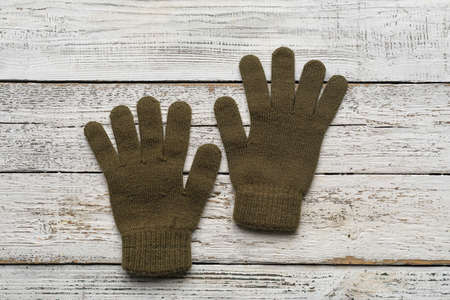 Pair of warm gloves on light wooden background