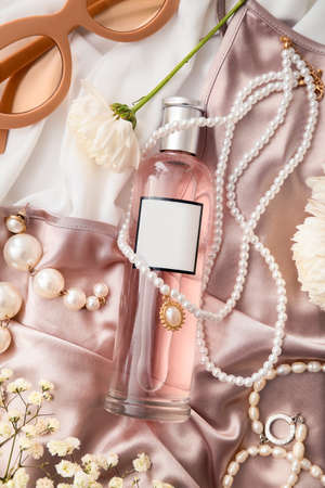 Stylish bottle of perfume and elegant female accessories on fabric backgroundの写真素材