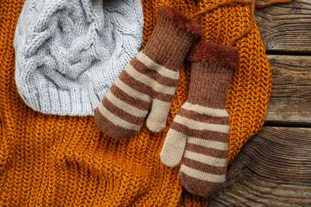 Warm mittens, clothes and hat on wooden background, closeupの写真素材