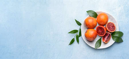 Plate of ripe blood oranges on light blue background with space for text, top viewの写真素材