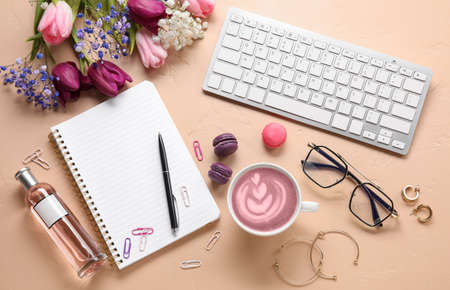 Cup of pink matcha tea, computer keyboard, notebook, flowers and female accessories on color...