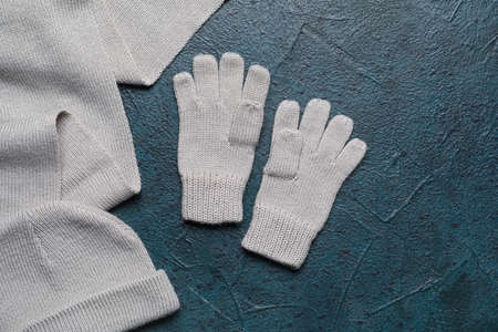 Warm gloves, hat and scarf on dark color background